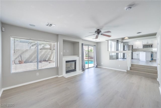 8712 Texas Bronco Ave, Las Vegas, NV 89129 - unfurnished living room featuring light wood finished floors, a ceiling fan, and a fireplace