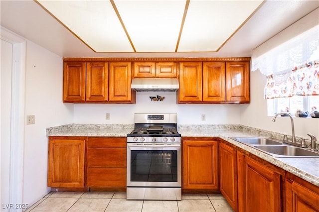 5673 Coaldale Pl, Las Vegas, NV 89110 - kitchen featuring under cabinet range hood, stainless steel gas range, brown cabinetry, and light countertops