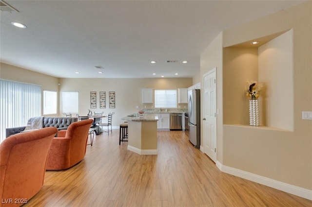 10243 Songsparrow Ct, Las Vegas, NV 89135 - kitchen featuring appliances with stainless steel finishes, open floor plan, white cabinetry, light wood-style floors, and plenty of natural light