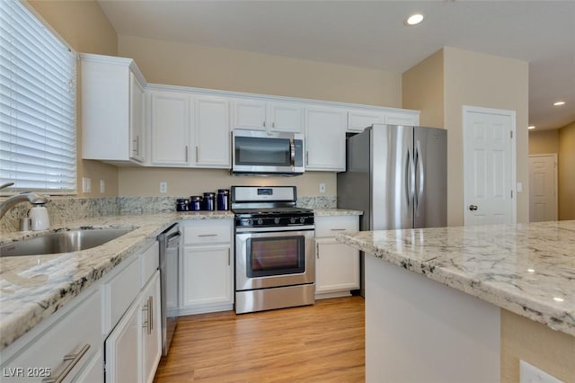 10243 Songsparrow Ct, Las Vegas, NV 89135 - kitchen featuring appliances with stainless steel finishes, white cabinets, light wood-style flooring, light stone counters, and recessed lighting