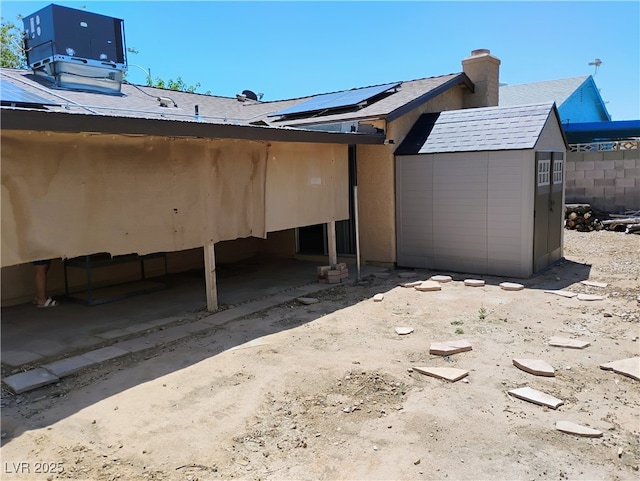608 Watkins Dr, Las Vegas, NV 89107 - back of house featuring roof mounted solar panels, a chimney, and a storage shed