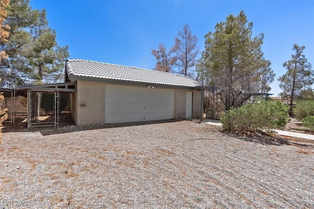 5981 Doubletree Rd, Pahrump, NV 89061 - view of side of home featuring stucco siding, a tiled roof, an attached garage, and driveway