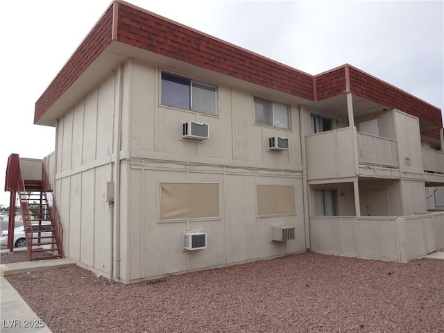 5388 Swenson St Unit 26, Las Vegas, NV 89119 - view of property exterior featuring stairway, mansard roof, a shingled roof, and an AC wall unit