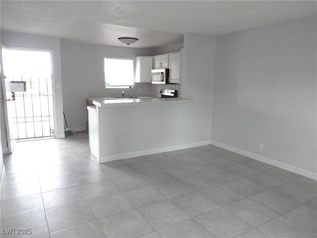5388 Swenson St Unit 26, Las Vegas, NV 89119 - kitchen featuring stainless steel microwave, white cabinetry, light countertops, a peninsula, and a textured ceiling