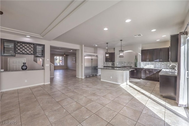 9876 Parador Cellars Ct, Las Vegas, NV 89141 - kitchen with stainless steel built in fridge, backsplash, light tile patterned floors, recessed lighting, and dark brown cabinetry