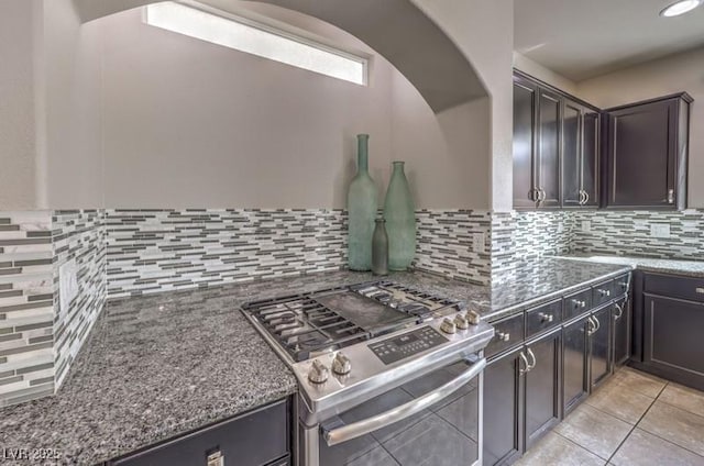 9876 Parador Cellars Ct, Las Vegas, NV 89141 - kitchen with stainless steel gas range, arched walkways, dark stone countertops, backsplash, and light tile patterned flooring