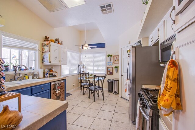 8324 Tide Pool Dr, Las Vegas, NV 89128 - kitchen with appliances with stainless steel finishes, blue cabinetry, white cabinets, light tile patterned flooring, and lofted ceiling