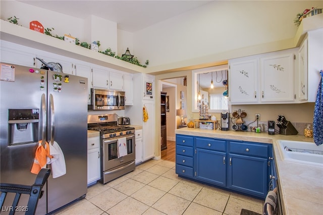 8324 Tide Pool Dr, Las Vegas, NV 89128 - kitchen featuring stainless steel appliances, blue cabinets, white cabinets, light countertops, and light tile patterned flooring