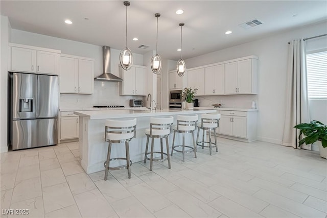 827 Klamath Springs St, Henderson, NV 89011 - kitchen featuring stainless steel appliances, wall chimney range hood, light countertops, a breakfast bar area, and an island with sink