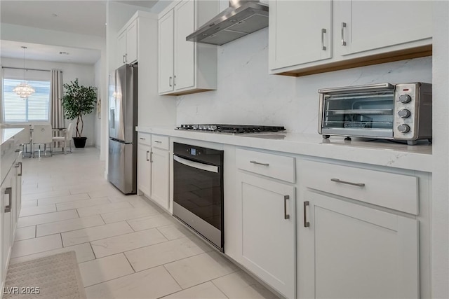 827 Klamath Springs St, Henderson, NV 89011 - kitchen with appliances with stainless steel finishes, wall chimney range hood, light countertops, and a chandelier