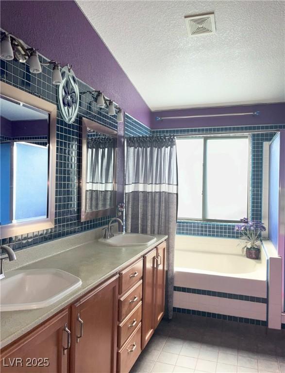 5929 Gentle Creek Ln, North Las Vegas, NV 89031 - bathroom featuring double vanity, a textured ceiling, tile patterned floors, a textured wall, and tiled shower / bath combo