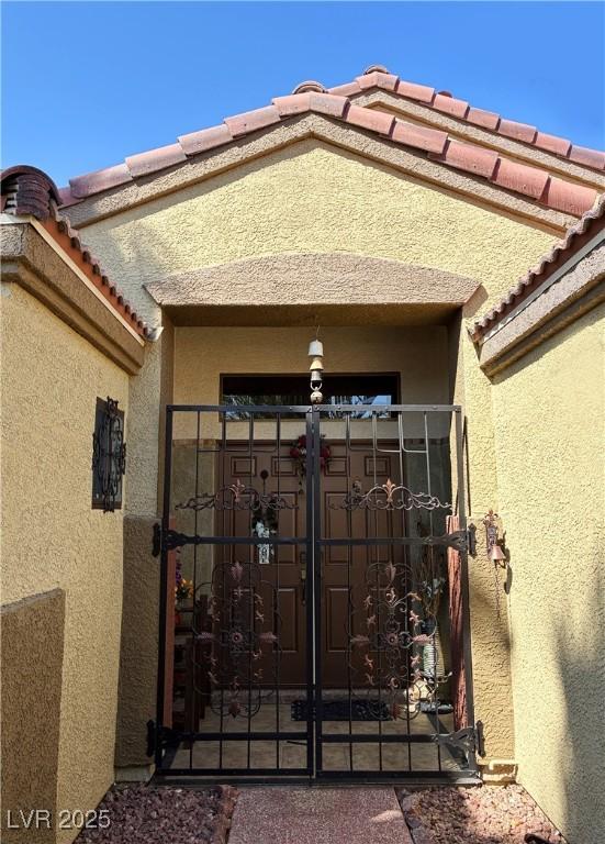 5929 Gentle Creek Ln, North Las Vegas, NV 89031 - doorway to property with stucco siding, a gate, and a tiled roof