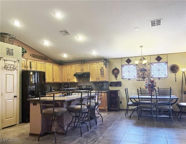 5929 Gentle Creek Ln, North Las Vegas, NV 89031 - kitchen featuring under cabinet range hood, decorative backsplash, light brown cabinetry, a breakfast bar, and black fridge