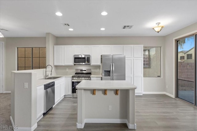 6460 Raven Hall St, North Las Vegas, NV 89084 - kitchen with appliances with stainless steel finishes, wood finished floors, a kitchen island, white cabinets, and recessed lighting