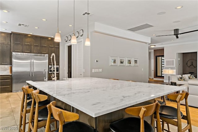 1509 Winslow St, Las Vegas, NV 89117 - kitchen with built in refrigerator, dark brown cabinets, a kitchen bar, open floor plan, and light tile patterned flooring