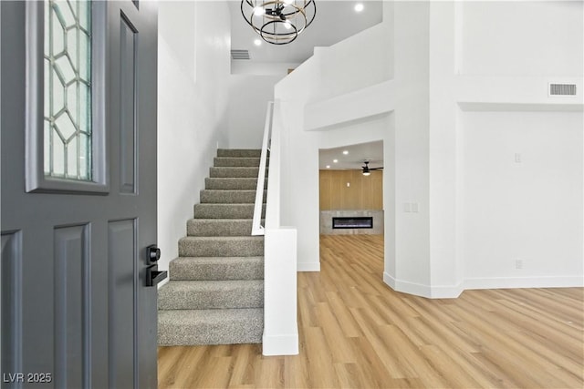 2105 Madagascar Ln, Las Vegas, NV 89117 - foyer entrance featuring light wood-style flooring, stairway, recessed lighting, a glass covered fireplace, and a chandelier