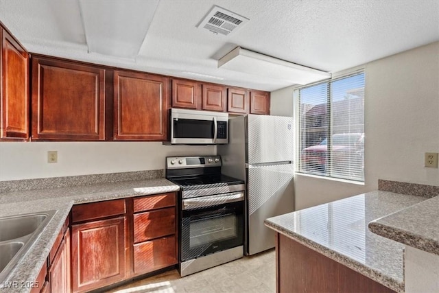 5200 Indian River Dr Unit 301, Las Vegas, NV 89103 - kitchen featuring appliances with stainless steel finishes, a peninsula, and a textured ceiling
