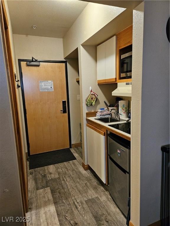 223 Hunter Ridge Rd Unit 121, Brian Head, UT 84719 - kitchen with dark wood-type flooring, white cabinets, stainless steel microwave, under cabinet range hood, and light countertops