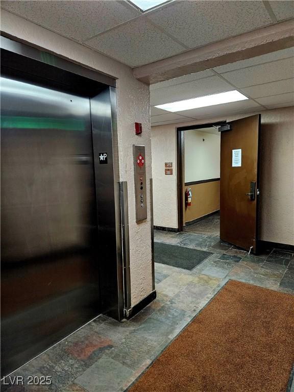 223 Hunter Ridge Rd Unit 121, Brian Head, UT 84719 - hallway featuring stone tile floors, elevator, and a drop ceiling