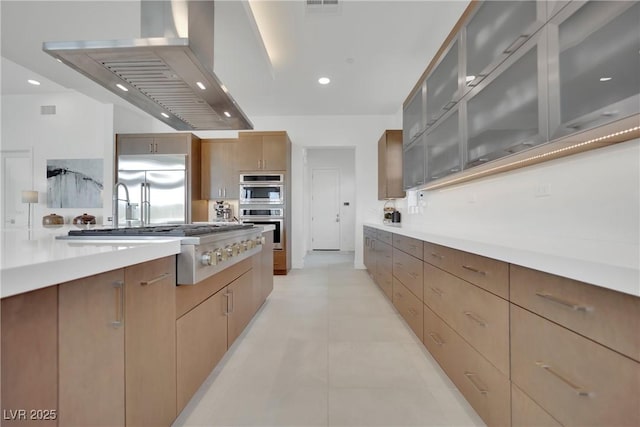 818 Calluna St, Las Vegas, NV 89138 - kitchen featuring stainless steel appliances, wall chimney exhaust hood, light countertops, glass insert cabinets, and modern cabinets