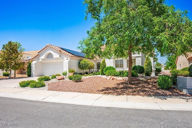 9704 Brawley Dr, Las Vegas, NV 89134 - view of front facade with an attached garage, roof mounted solar panels, stucco siding, concrete driveway, and a tile roof