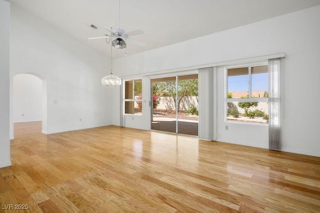 9704 Brawley Dr, Las Vegas, NV 89134 - spare room featuring arched walkways, wood finished floors, a chandelier, a ceiling fan, and a towering ceiling