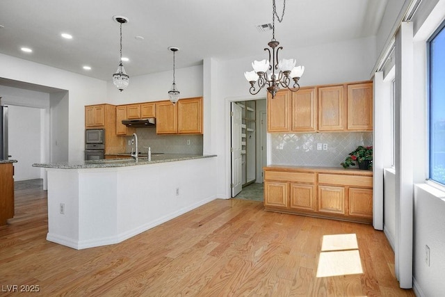 9704 Brawley Dr, Las Vegas, NV 89134 - kitchen with under cabinet range hood, light wood finished floors, tasteful backsplash, pendant lighting, and recessed lighting