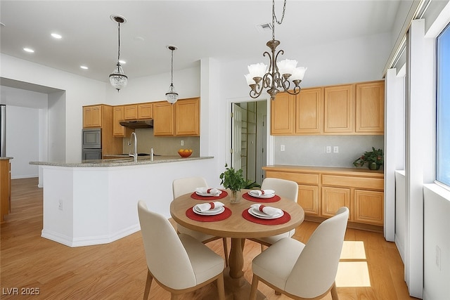 9704 Brawley Dr, Las Vegas, NV 89134 - kitchen featuring under cabinet range hood, light wood finished floors, stainless steel microwave, a chandelier, and pendant lighting