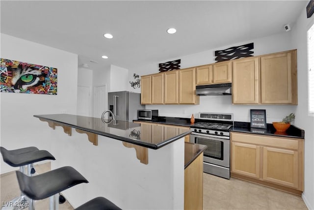 10045 Natchez Trace St, Las Vegas, NV 89178 - kitchen featuring stainless steel appliances, under cabinet range hood, light brown cabinets, dark countertops, and recessed lighting