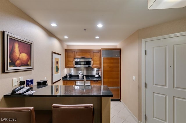 135 E Harmon Ave Unit 2821, Las Vegas, NV 89109 - kitchen featuring paneled fridge, stainless steel microwave, brown cabinets, a peninsula, and light tile patterned floors