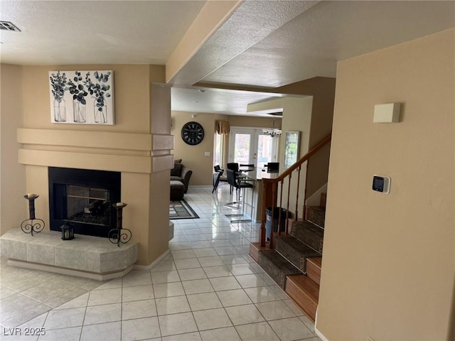8225 Bermuda Beach Dr, Las Vegas, NV 89128 - tiled living area featuring stairs, a tiled fireplace, a chandelier, and a textured ceiling