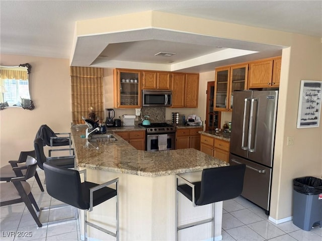 8225 Bermuda Beach Dr, Las Vegas, NV 89128 - kitchen featuring stainless steel appliances, a peninsula, brown cabinetry, and a kitchen breakfast bar