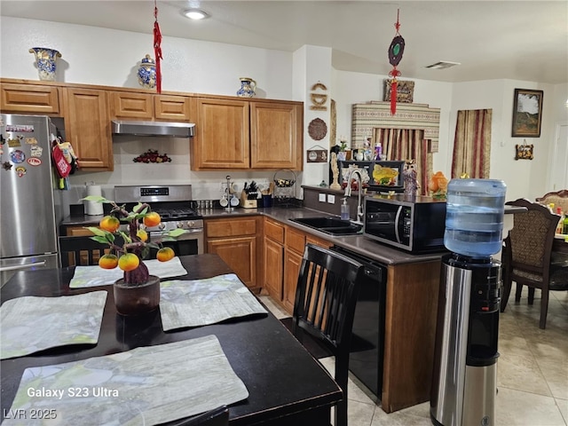 5651 Bettors Luck Ct, Las Vegas, NV 89122 - kitchen featuring appliances with stainless steel finishes, under cabinet range hood, dark countertops, light tile patterned flooring, and brown cabinets