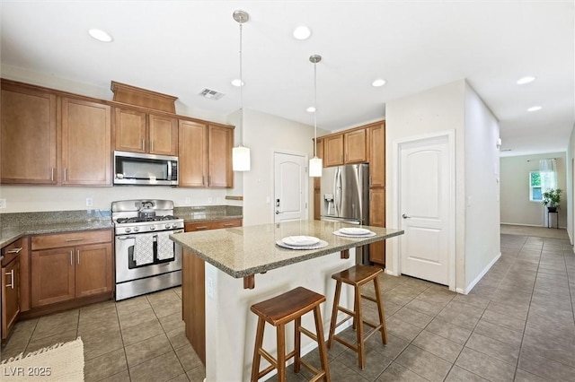 6713 Guidestar St, North Las Vegas, NV 89084 - kitchen featuring stainless steel appliances, tile patterned flooring, a kitchen island, brown cabinets, and a breakfast bar