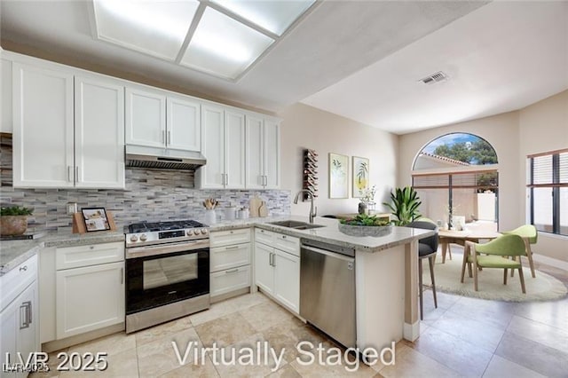 2723 Seabridge Dr, Las Vegas, NV 89121 - kitchen with stainless steel appliances, under cabinet range hood, decorative backsplash, and a peninsula