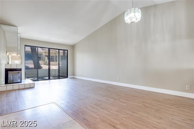 2723 Seabridge Dr, Las Vegas, NV 89121 - unfurnished living room featuring lofted ceiling, wood finished floors, a chandelier, and a tile fireplace