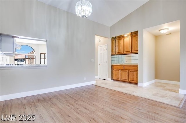 2723 Seabridge Dr, Las Vegas, NV 89121 - unfurnished living room featuring light wood finished floors, high vaulted ceiling, and a chandelier