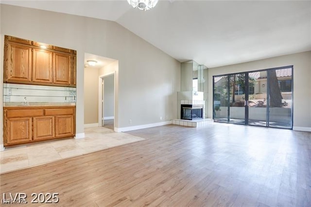 2723 Seabridge Dr, Las Vegas, NV 89121 - unfurnished living room with lofted ceiling, light wood-type flooring, and a tiled fireplace