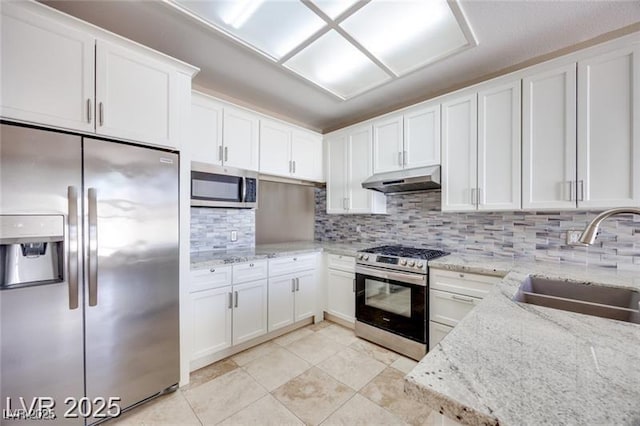 2723 Seabridge Dr, Las Vegas, NV 89121 - kitchen featuring stainless steel appliances, under cabinet range hood, decorative backsplash, white cabinetry, and light stone countertops