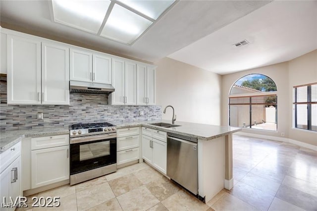 2723 Seabridge Dr, Las Vegas, NV 89121 - kitchen with appliances with stainless steel finishes, under cabinet range hood, backsplash, a peninsula, and white cabinetry