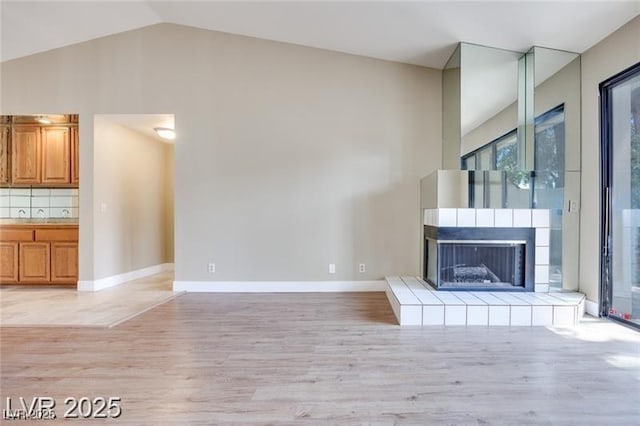 2723 Seabridge Dr, Las Vegas, NV 89121 - unfurnished living room featuring light wood finished floors, lofted ceiling, and a tiled fireplace