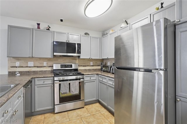 7640 Woven Memories St, Las Vegas, NV 89149 - kitchen with appliances with stainless steel finishes, gray cabinetry, decorative backsplash, and light tile patterned floors