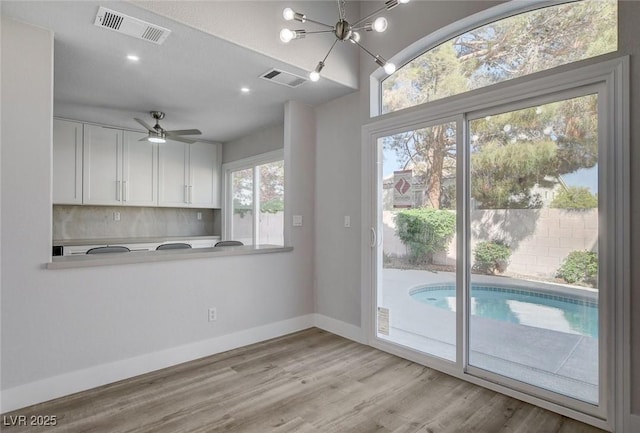 2212 Warm Walnut Dr, Las Vegas, NV 89134 - kitchen featuring white cabinets, tasteful backsplash, wood finished floors, light countertops, and a chandelier