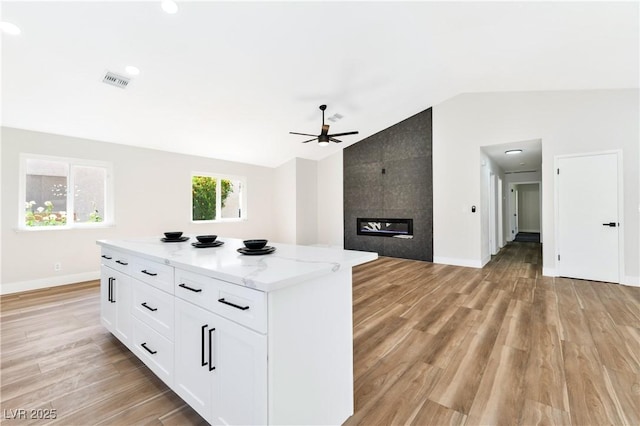 811 Spyglass Ln, Las Vegas, NV 89107 - kitchen featuring lofted ceiling, a ceiling fan, a kitchen island, white cabinetry, and light stone countertops