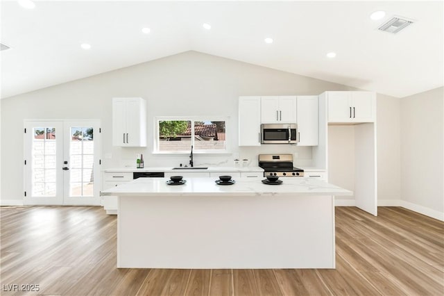 811 Spyglass Ln, Las Vegas, NV 89107 - kitchen with stainless steel microwave, range, a center island, vaulted ceiling, and light countertops