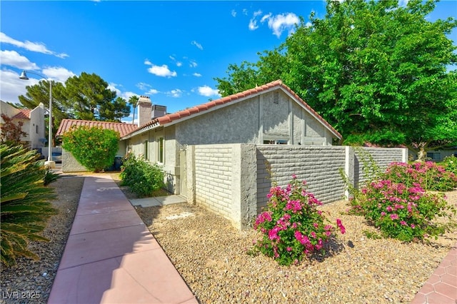 811 Spyglass Ln, Las Vegas, NV 89107 - view of property exterior with a chimney, stucco siding, and a tiled roof