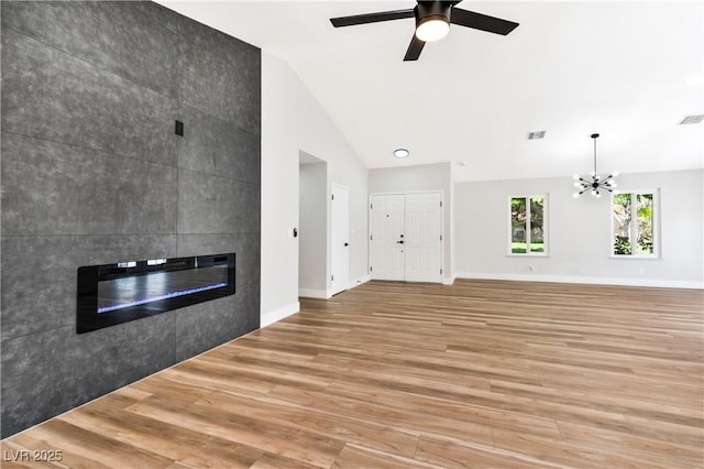 811 Spyglass Ln, Las Vegas, NV 89107 - unfurnished living room featuring light wood finished floors, a tiled fireplace, lofted ceiling, a ceiling fan, and a chandelier