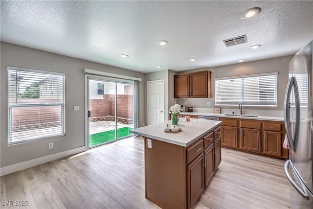 9129 Patrick Henry Ave, Las Vegas, NV 89149 - kitchen featuring appliances with stainless steel finishes, brown cabinetry, light countertops, a textured ceiling, and a kitchen island