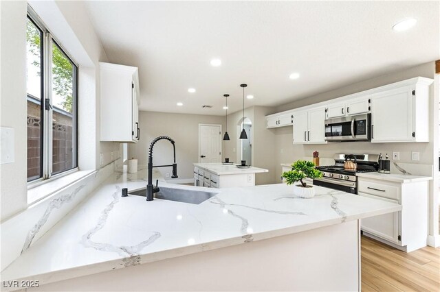 8113 Bay Springs Dr, Las Vegas, NV 89128 - kitchen featuring appliances with stainless steel finishes, a peninsula, recessed lighting, light wood finished floors, and white cabinetry