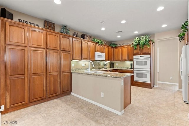8623 Kennedy Heights Ct, Las Vegas, NV 89131 - kitchen with white appliances, recessed lighting, a peninsula, brown cabinets, and light stone counters